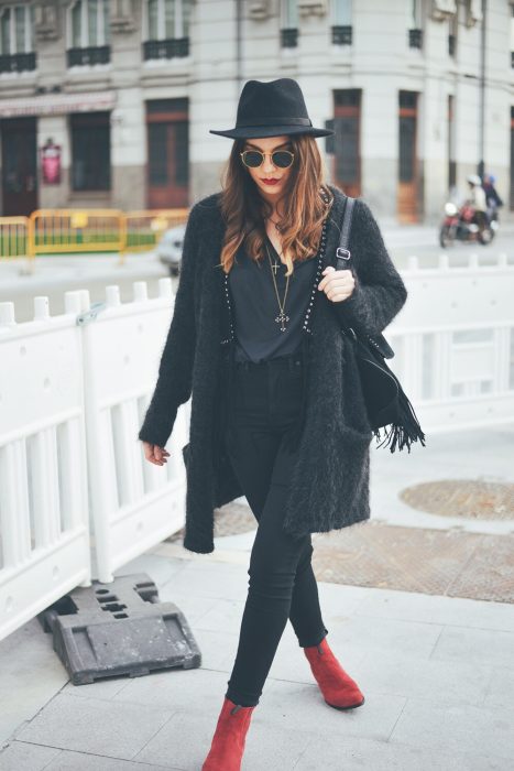 Chica caminando por la ciudad con outfit y sombrero negro y botines rojos