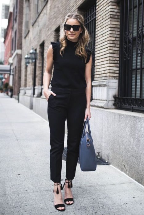 Mujer joven vestida de negro con bolsa azul caminando por la calle