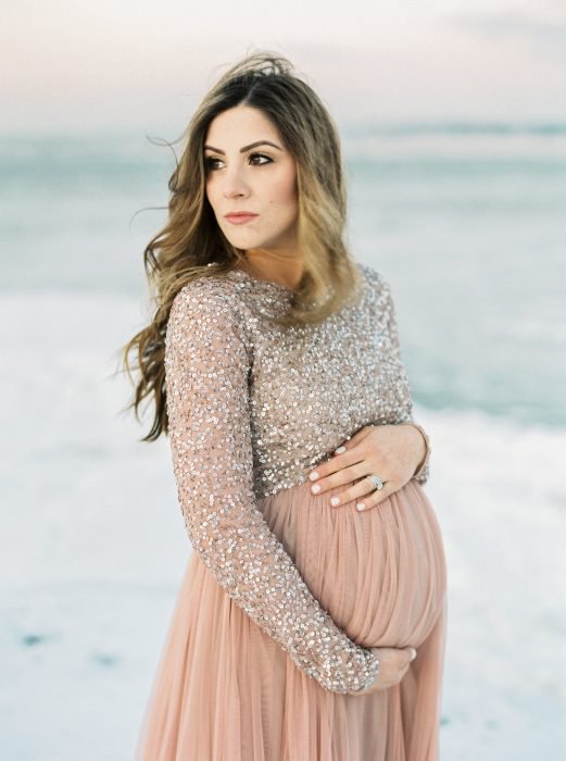 Vestidos para baby shower, sesión fotográfica de embarazo en la playa, mujer rubia de cabello largo con vestido rosa salmón y top de lentejuelas de manga larga