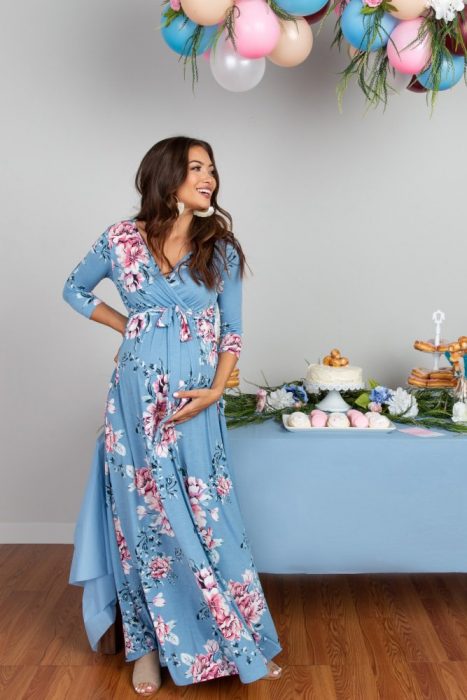 Mujer de cabello castaño embarazada, usando vestido azul, largo y holgado de flores rosas, festejando baby shower de niño