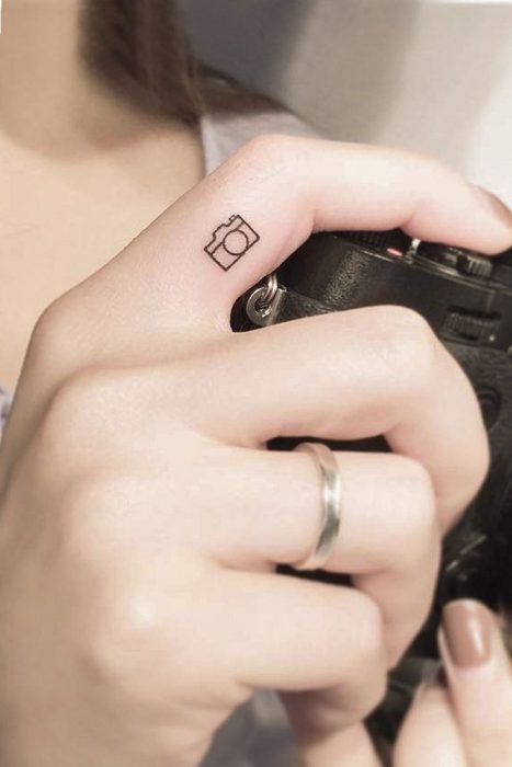 Tatuaje pequeño de una cámara fotográfica en el dedo de la mano 