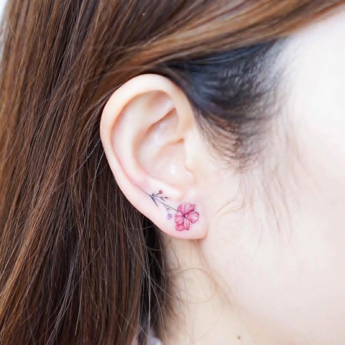 Tatuaje pequeño de una flor en el lóbulo de la oreja