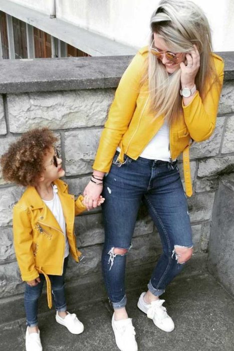 Madre e hija usando chaquetas amarillas de cuero con jeans de mezclilla y camisas blancas