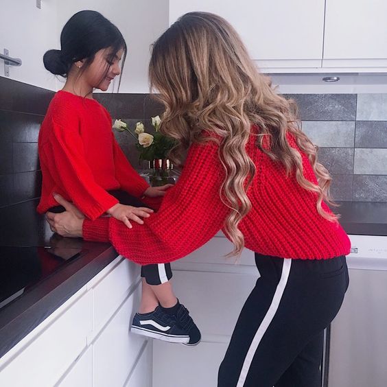 Madre e hija con pants deposrtivos en negro y suéteres rojos de estambres