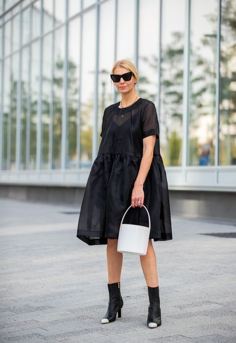Chica usando un vestido de color negro con unos botines de color negro con punta blanca 