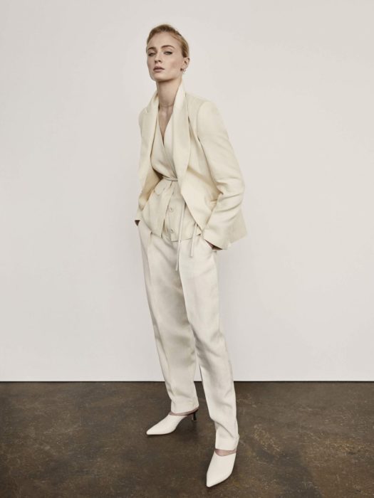 Famosas con traje; Sophie Turner con saco y pantalón de gala color blanco marfil, y peinado de cola de caballo sencillo