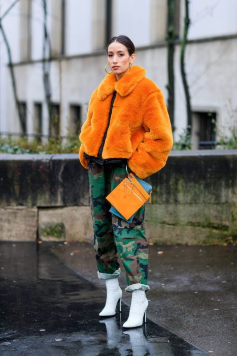 Chica usando un abrigo de color naranja con un pantalón verde militar 