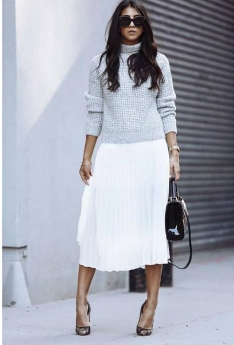 Chica con suéter gris y falda plisada blanca larga