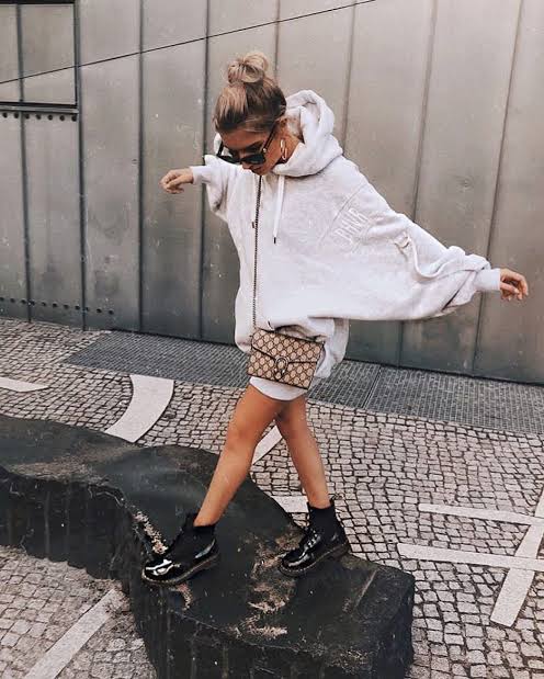 Chica con botas estilo milatr en negro y hoodie amplia en gris