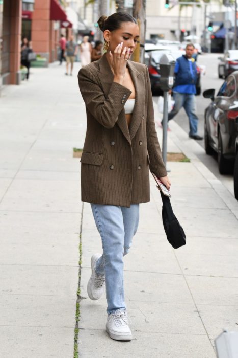 Chica usando un blazer de color café con jeans y tenis 