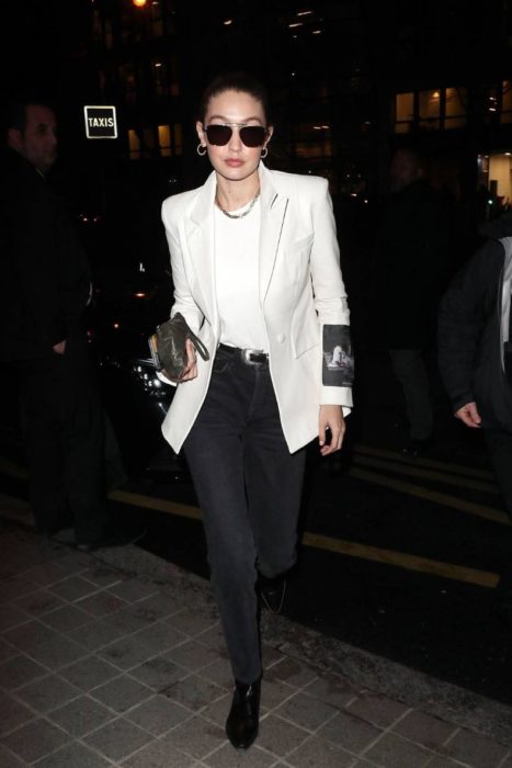 Gigi Hadid caminando por las calles mientras usa un blazer blanco con jeans negros 