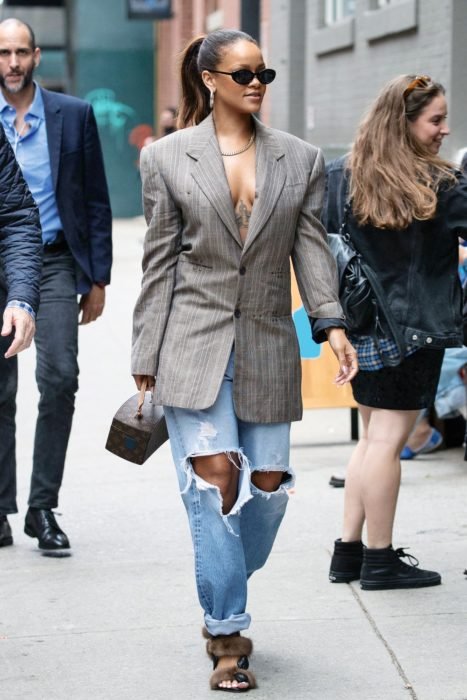 Rihanna caminando por la calle mientras usa un look de blazer con jeans 