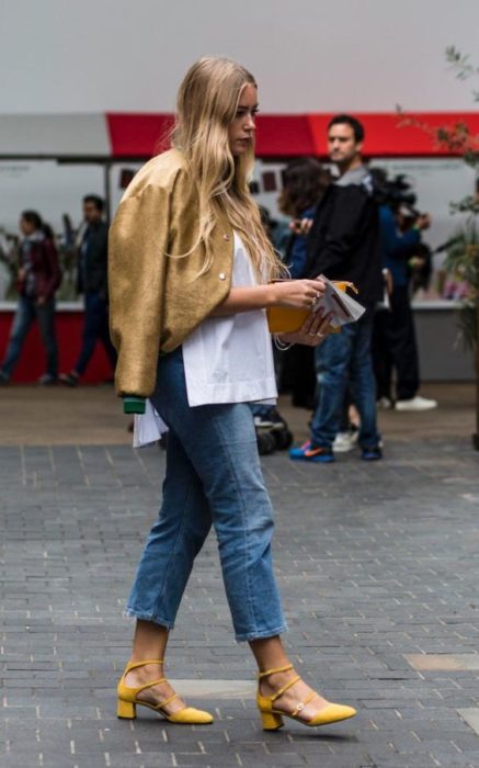 Mujer con cabellosuelto viste jeans, chaqueta dorada tacones cuadrados